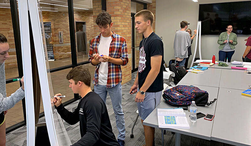 Students using one of the School of Business collaboration rooms