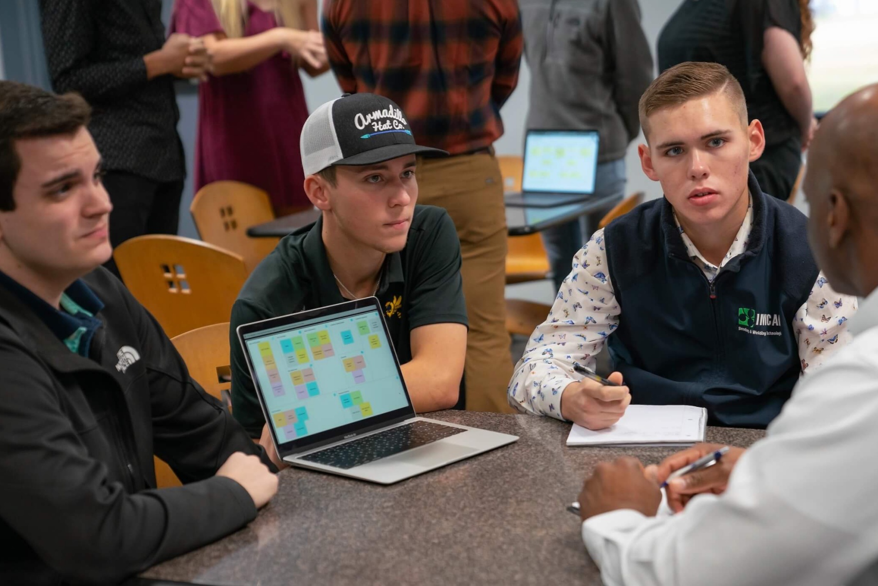 Business students sit around a table with a community business leader.