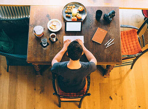 Man at table, writing on a computer